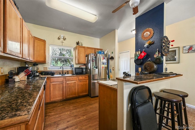 5720 County Road 64 # A102, Bailey, CO 80421 - kitchen with stainless steel fridge, black microwave, a peninsula, a kitchen bar, and brown cabinets