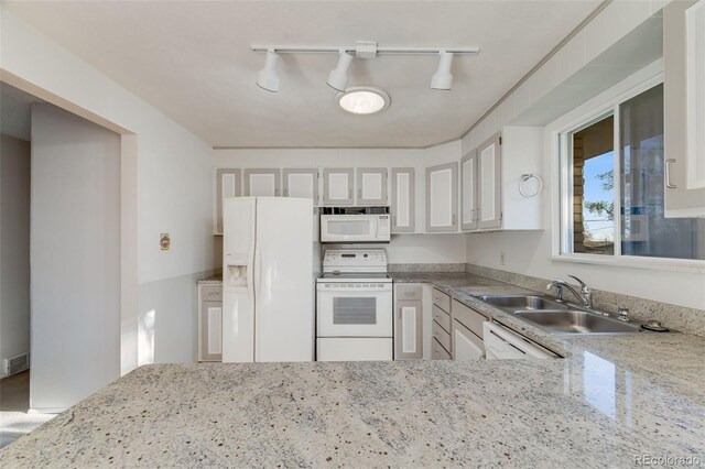 772 Urban Ct, Lakewood, CO 80401 - kitchen with white appliances, white cabinetry, rail lighting, light stone counters, and a sink
