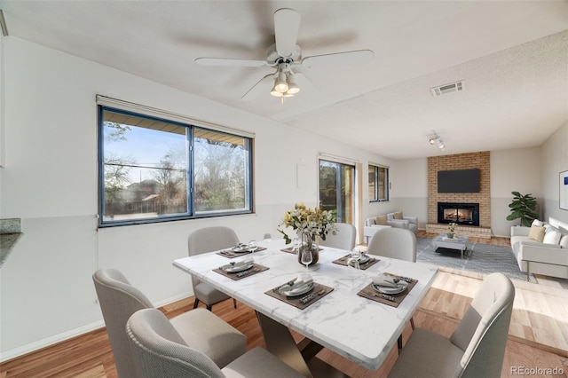 772 Urban Ct, Lakewood, CO 80401 - dining area featuring a ceiling fan, visible vents, a brick fireplace, wood finished floors, and baseboards