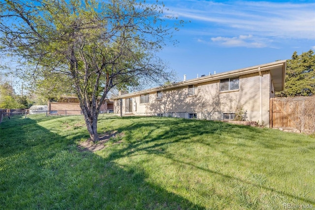 772 Urban Ct, Lakewood, CO 80401 - rear view of house with a lawn, brick siding, and fence