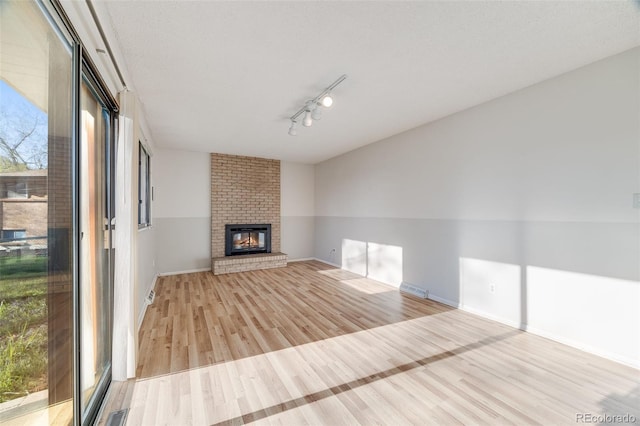 772 Urban Ct, Lakewood, CO 80401 - unfurnished living room with light wood finished floors, a fireplace, rail lighting, baseboards, and visible vents