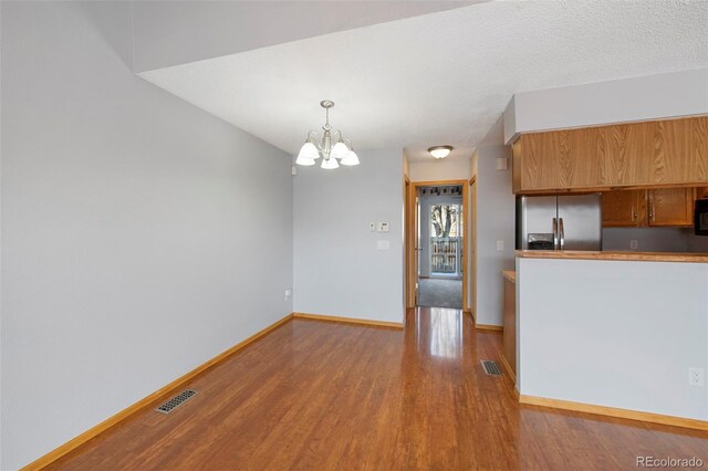 kitchen featuring hanging light fixtures, stainless steel refrigerator with ice dispenser, a notable chandelier, and light hardwood / wood-style floors