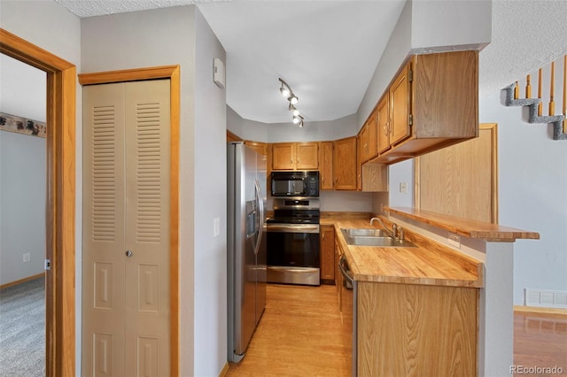 kitchen featuring track lighting, stainless steel appliances, light hardwood / wood-style floors, and sink