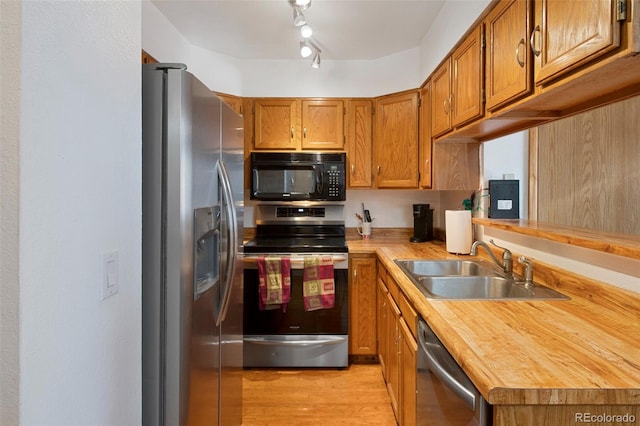 kitchen featuring wood counters, sink, stainless steel appliances, and light hardwood / wood-style floors