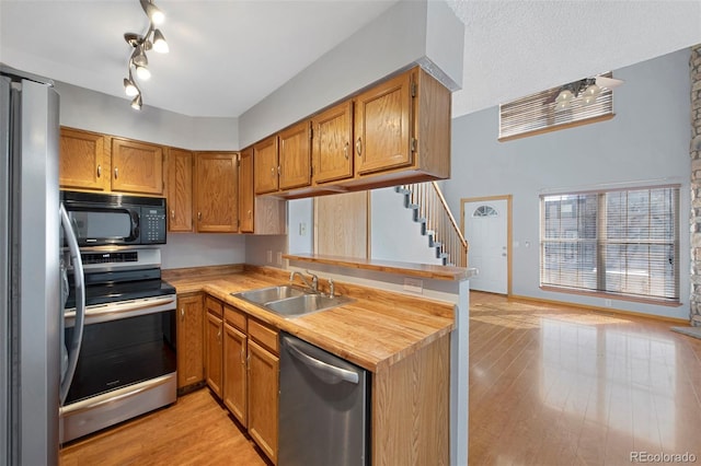 kitchen featuring sink, light hardwood / wood-style floors, kitchen peninsula, stainless steel appliances, and track lighting