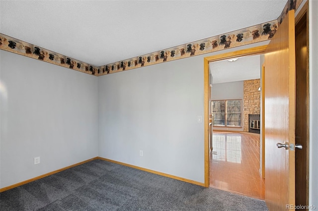 carpeted empty room featuring a large fireplace and a textured ceiling