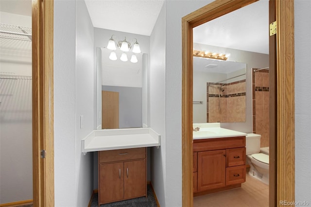 bathroom featuring tiled shower, vanity, toilet, and tile patterned floors