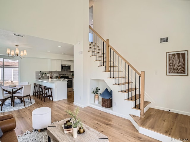 21472 E 46th Ave, Denver, CO 80249 - living room featuring a high ceiling, stairs, light wood-type flooring, and a chandelier
