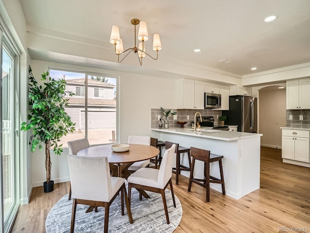 21472 E 46th Ave, Denver, CO 80249 - dining area featuring arched walkways, recessed lighting, light wood-type flooring, a chandelier, and baseboards