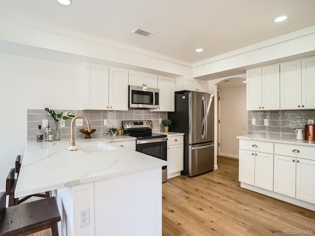 21472 E 46th Ave, Denver, CO 80249 - kitchen featuring appliances with stainless steel finishes, a sink, a peninsula, arched walkways, and tasteful backsplash