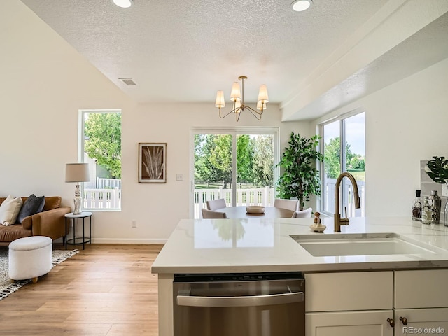 21472 E 46th Ave, Denver, CO 80249 - kitchen featuring stainless steel dishwasher, a sink, light wood finished floors, a chandelier, and a textured ceiling