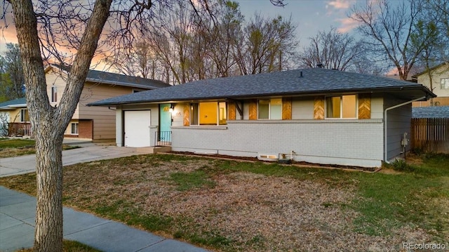 2121 Carmel Dr, Colorado Springs, CO 80910 - view of front facade featuring an attached garage, concrete driveway, fence, and brick siding