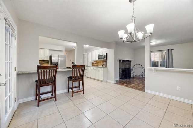 2121 Carmel Dr, Colorado Springs, CO 80910 - kitchen with an inviting chandelier, light tile patterned floors, a peninsula, white cabinetry, and stainless steel appliances