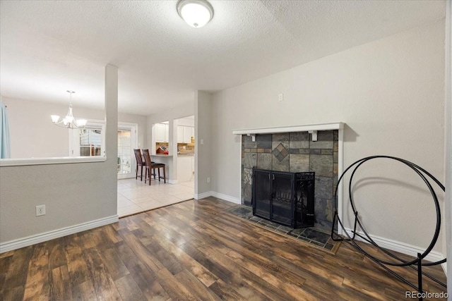2121 Carmel Dr, Colorado Springs, CO 80910 - unfurnished living room featuring a fireplace, a textured ceiling, wood finished floors, baseboards, and a notable chandelier