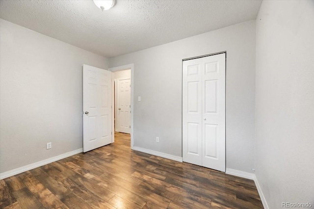 2121 Carmel Dr, Colorado Springs, CO 80910 - unfurnished bedroom featuring a closet, dark wood-type flooring, baseboards, and a textured ceiling