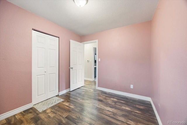 2121 Carmel Dr, Colorado Springs, CO 80910 - unfurnished bedroom featuring a closet, baseboards, a textured ceiling, and dark wood finished floors