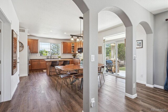 dining space featuring baseboards, arched walkways, dark wood-style flooring, and visible vents