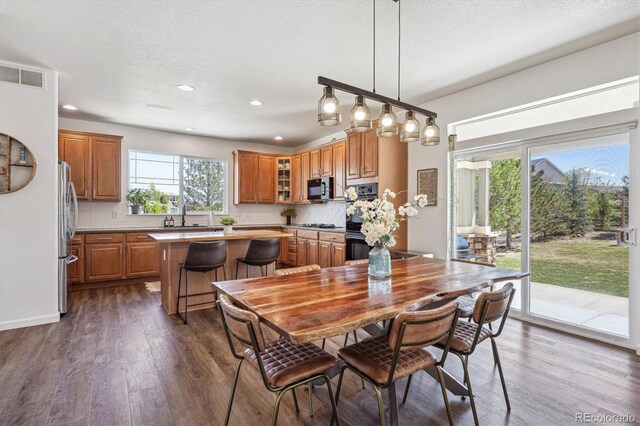 dining room featuring dark wood finished floors, recessed lighting, a textured ceiling, and visible vents