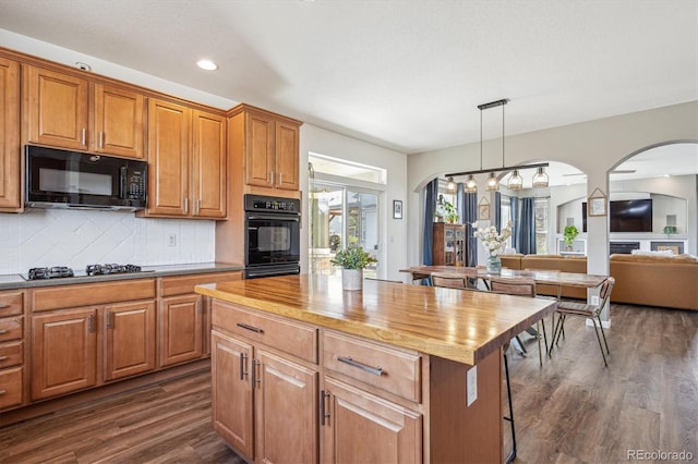 kitchen with arched walkways, butcher block counters, and black appliances