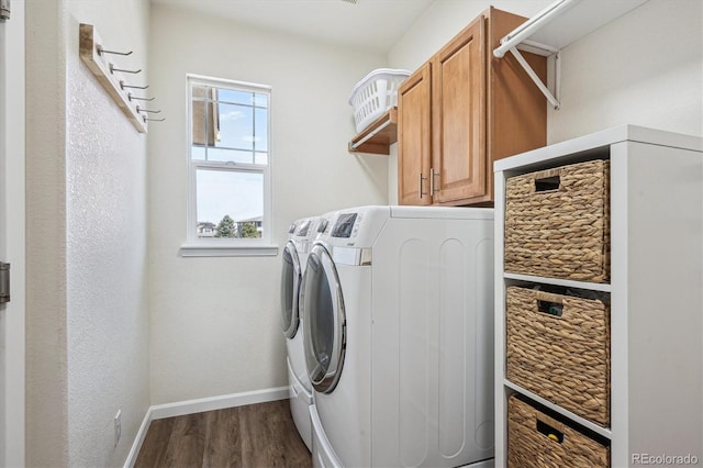 clothes washing area with baseboards, dark wood-type flooring, cabinet space, and washing machine and clothes dryer
