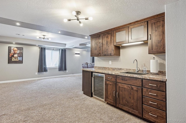 kitchen with light carpet, a sink, a textured ceiling, baseboards, and wine cooler