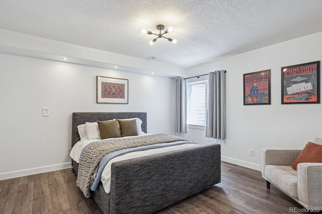 bedroom featuring baseboards, a textured ceiling, dark wood-style flooring, and a chandelier
