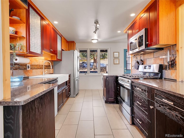 kitchen with light tile patterned floors, glass insert cabinets, tasteful backsplash, and appliances with stainless steel finishes