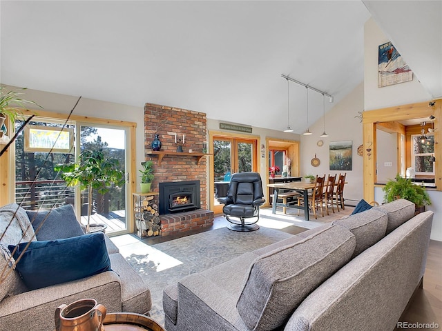 living room featuring track lighting, a fireplace, and high vaulted ceiling