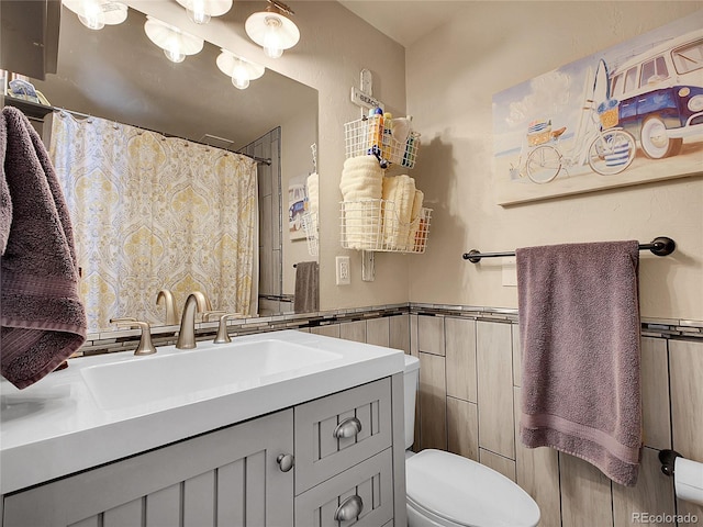 full bath featuring a wainscoted wall, curtained shower, toilet, and vanity