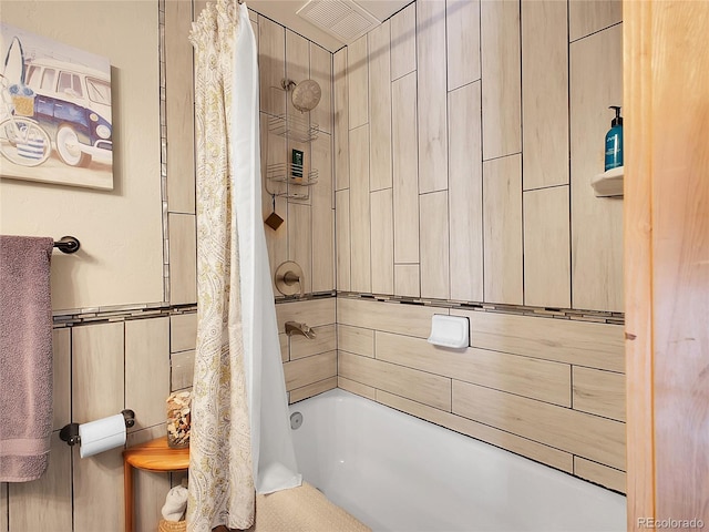 bathroom featuring tile walls and shower / bath combo with shower curtain