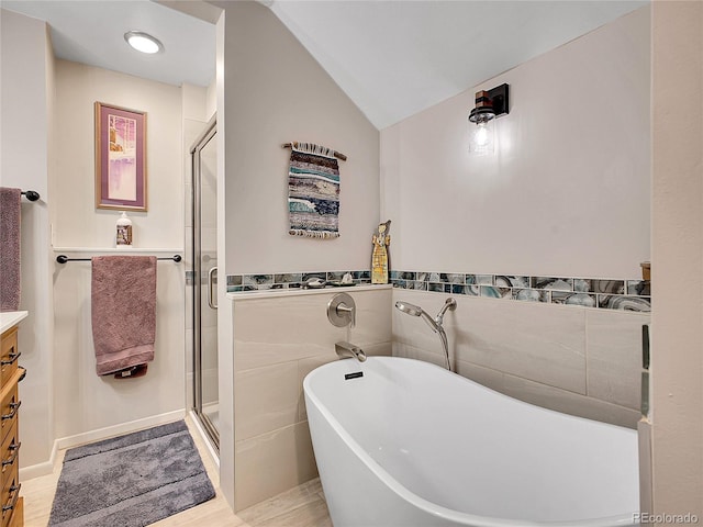 full bath with a freestanding tub, a stall shower, vanity, and vaulted ceiling