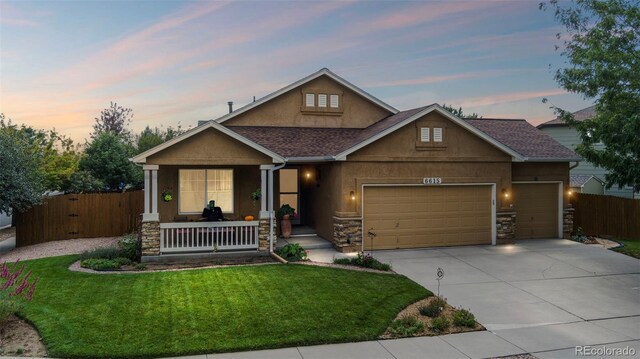 6615 Annanhill Pl, Colorado Springs, CO 80922 - view of front of house featuring covered porch, stone siding, a garage, concrete driveway, and roof with shingles