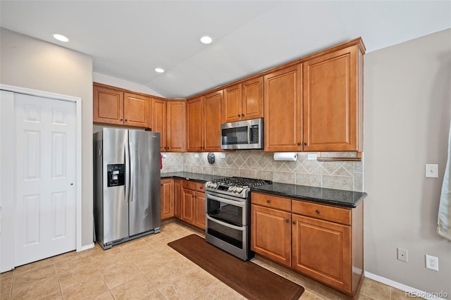 6615 Annanhill Pl, Colorado Springs, CO 80922 - kitchen featuring appliances with stainless steel finishes, backsplash, brown cabinets, vaulted ceiling, and light tile patterned floors