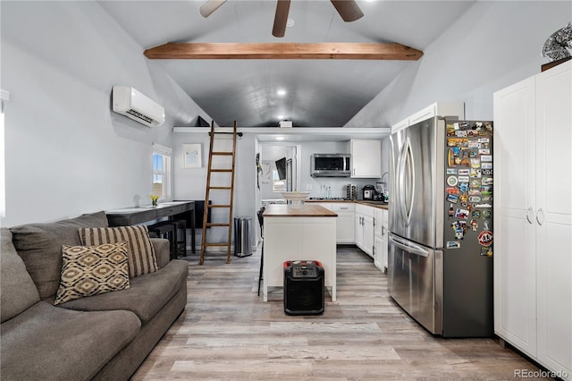 kitchen with lofted ceiling with beams, open floor plan, a wall mounted air conditioner, stainless steel appliances, and light wood-style floors