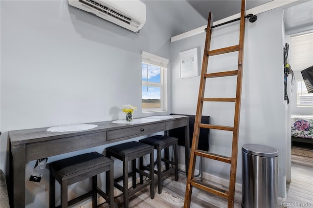 dining room featuring an AC wall unit and wood finished floors