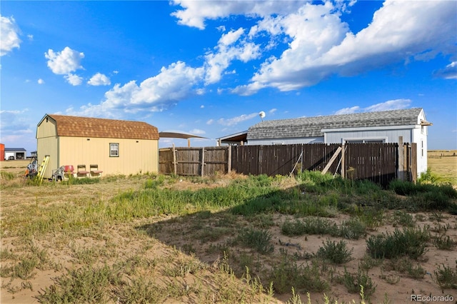 view of yard with a storage unit, fence, and an outbuilding