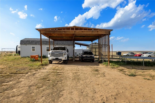 view of parking / parking lot with a detached carport and dirt driveway