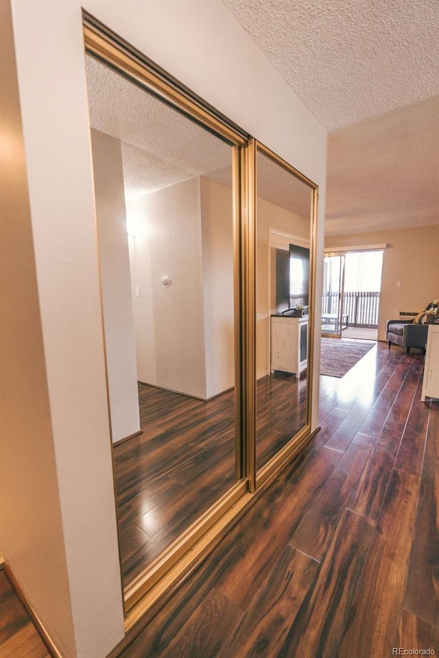 hall with a textured ceiling and wood finished floors