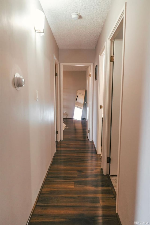 hallway featuring dark wood-style floors and a textured ceiling