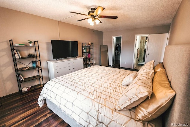 bedroom featuring dark wood finished floors, a ceiling fan, a walk in closet, a textured ceiling, and a closet