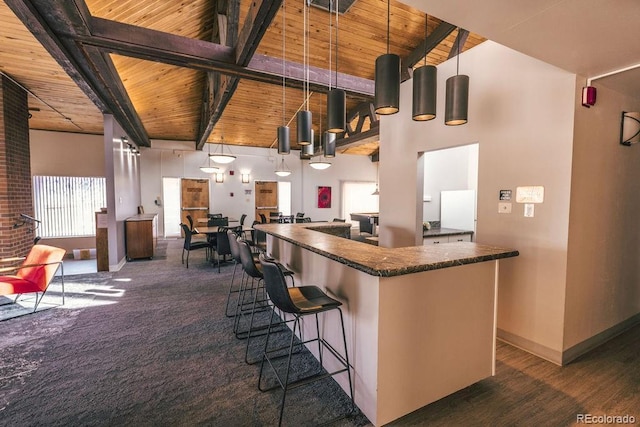 kitchen with a center island, a towering ceiling, wood ceiling, beamed ceiling, and baseboards