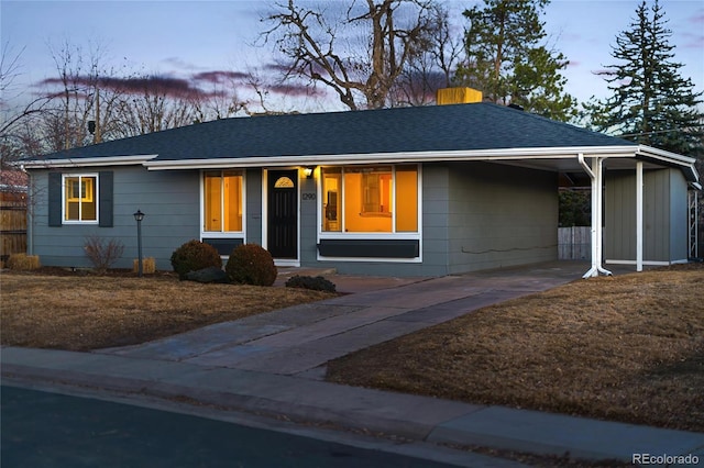 single story home featuring a shingled roof, an attached carport, driveway, and a front yard