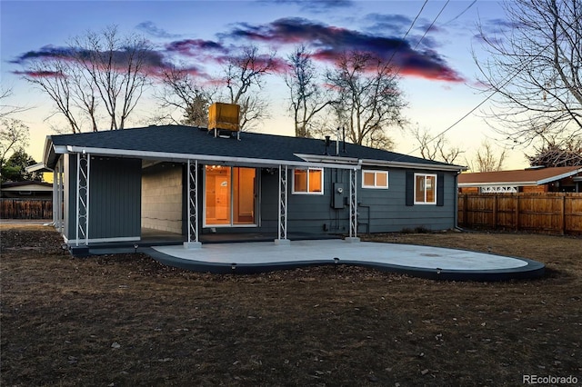 back of house at dusk featuring fence and a patio