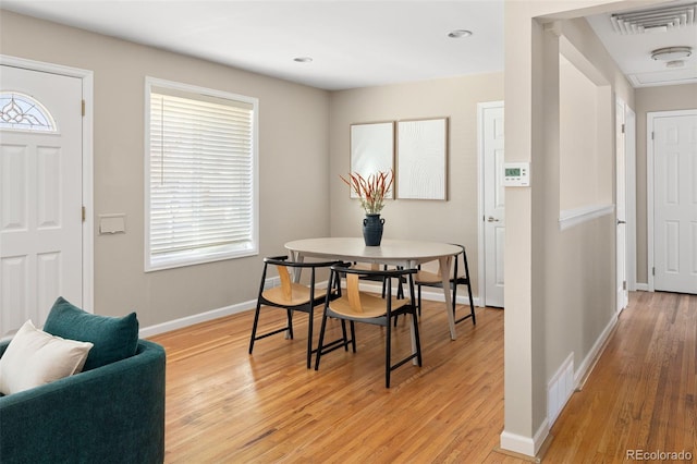 dining area with light wood-type flooring, visible vents, and baseboards