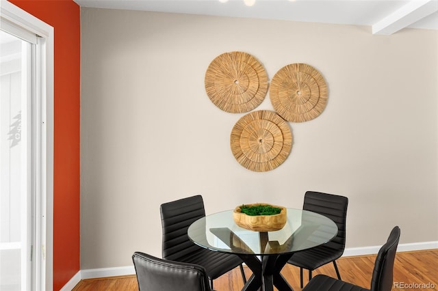 dining room featuring beam ceiling, baseboards, and wood finished floors