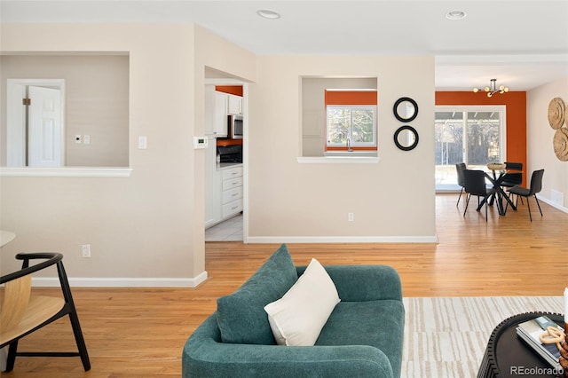 living area with a chandelier, light wood finished floors, recessed lighting, and baseboards