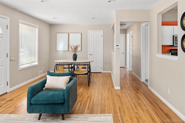 living area with light wood-type flooring, visible vents, baseboards, and recessed lighting