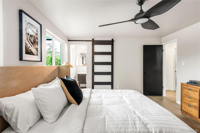 10000 E Ohio Ave, Denver, CO 80247 - bedroom featuring a barn door, wood finished floors, ceiling fan, and baseboards