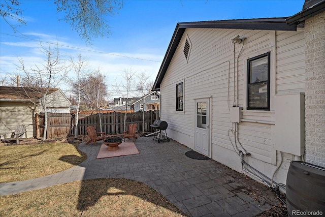 view of property exterior with fence, a patio area, and an outdoor fire pit