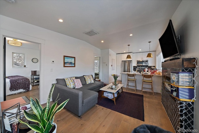 living area with light wood finished floors, vaulted ceiling, visible vents, and recessed lighting